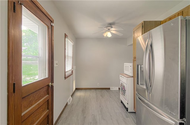 2917 N 83rd Ter, Kansas City, KS 66109 - kitchen with stainless steel fridge, white microwave, a ceiling fan, light wood-type flooring, and baseboards