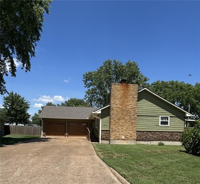 1205 W 14th Street Ct, Chanute, KS 66720 - view of front facade featuring a chimney, concrete driveway, an attached garage, and stone siding
