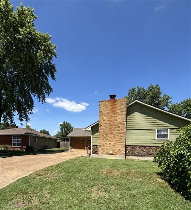 1205 W 14th Street Ct, Chanute, KS 66720 - view of side of property featuring a chimney, a yard, a garage, and stone siding