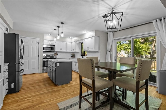 9327 Tomashaw Ln, Lenexa, KS 66219 - kitchen with appliances with stainless steel finishes, a center island, light wood-type flooring, white cabinetry, and pendant lighting
