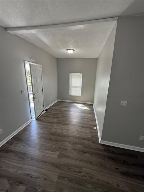 3318 E 24th St, Kansas City, MO 64127 - empty room featuring a textured ceiling, healthy amount of natural light, dark wood finished floors, and baseboards