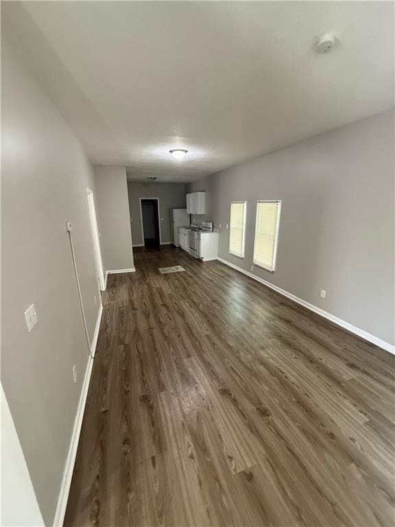 3318 E 24th St, Kansas City, MO 64127 - unfurnished living room featuring baseboards and dark wood-style floors