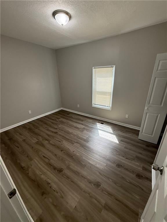 3318 E 24th St, Kansas City, MO 64127 - spare room with a textured ceiling, dark wood finished floors, and baseboards