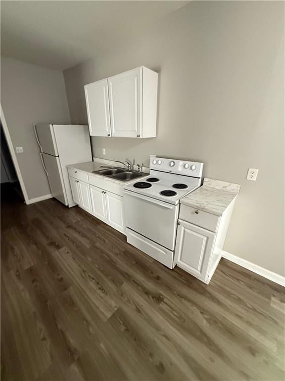 3318 E 24th St, Kansas City, MO 64127 - kitchen featuring white appliances, dark wood-type flooring, a sink, white cabinets, and baseboards