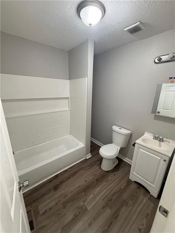 3318 E 24th St, Kansas City, MO 64127 - bathroom featuring toilet, vanity, wood finished floors, a textured ceiling, and baseboards