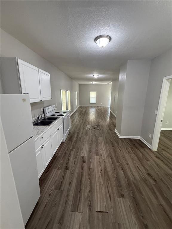 3318 E 24th St, Kansas City, MO 64127 - kitchen featuring white appliances, dark wood-style flooring, open floor plan, white cabinetry, and a textured ceiling