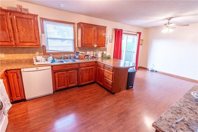 2802 N 39th Ter, Saint Joseph, MO 64506 - kitchen with white dishwasher, a sink, a peninsula, a ceiling fan, and light wood-style flooring