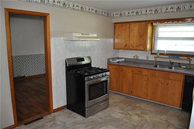 913 N Maple St, Stanberry, MO 64489 - kitchen featuring stainless steel gas range oven, a sink, under cabinet range hood, brown cabinetry, and wainscoting