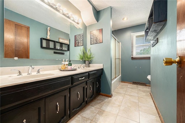 63 Maple Dr, Platte City, MO 64079 - bathroom with double vanity, tile patterned floors, a textured ceiling, and combined bath / shower with glass door