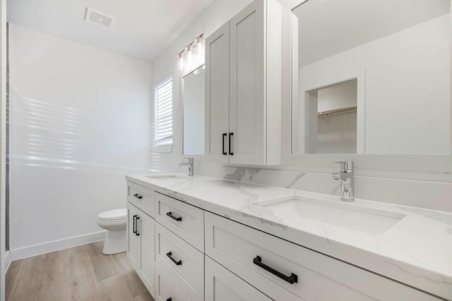 3818 NW 93rd St, Kansas City, MO 64154 - full bathroom featuring double vanity, toilet, wood finished floors, and a closet