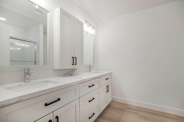 3818 NW 93rd St, Kansas City, MO 64154 - bathroom featuring double vanity, wood finished floors, a shower with shower door, and baseboards