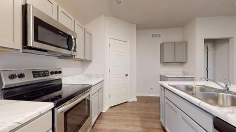 551 W Lanesfield St, Gardner, KS 66030 - kitchen with appliances with stainless steel finishes, a sink, wood finished floors, light countertops, and baseboards