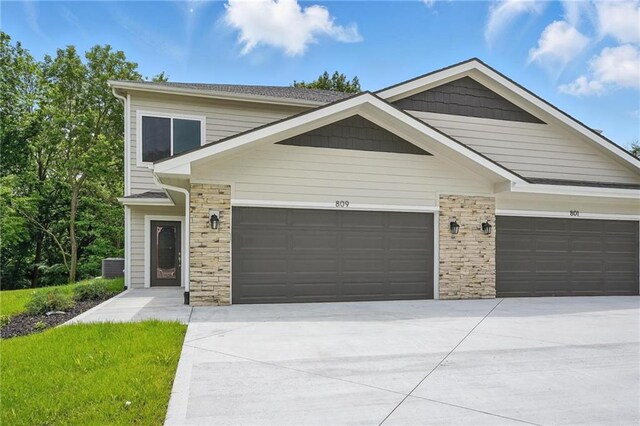 809 Highland Dr, Edwardsville, KS 66111 - view of front of property featuring a garage, stone siding, concrete driveway, and cooling unit