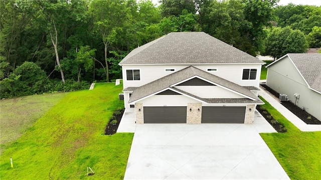 809 Highland Dr, Edwardsville, KS 66111 - view of front of home featuring a shingled roof, concrete driveway, a front yard, and central AC