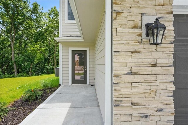 809 Highland Dr, Edwardsville, KS 66111 - doorway to property featuring stone siding and central AC unit