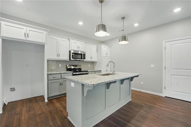 809 Highland Dr, Edwardsville, KS 66111 - kitchen with stainless steel appliances, a sink, a kitchen breakfast bar, dark wood-type flooring, and a center island with sink