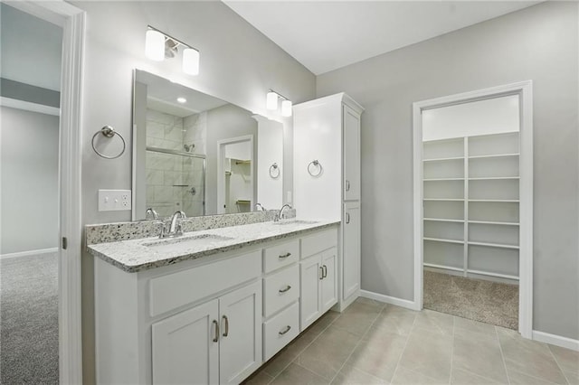 809 Highland Dr, Edwardsville, KS 66111 - full bathroom with a walk in closet, a shower stall, baseboards, double vanity, and tile patterned floors