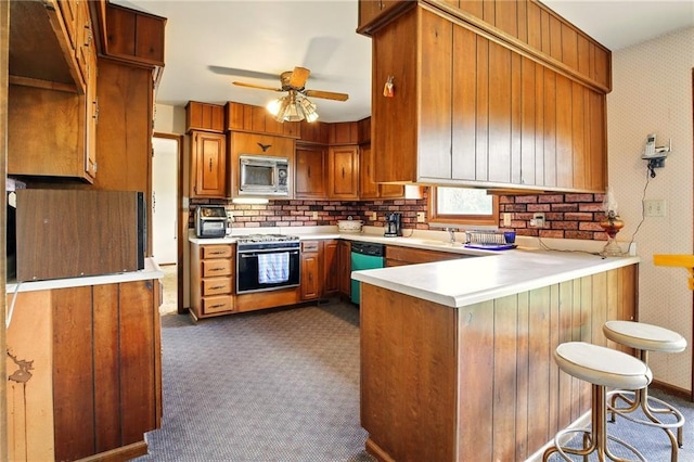 4613 SE Atchison Rd, Lathrop, MO 64465 - kitchen featuring stainless steel microwave, dishwashing machine, a peninsula, dark carpet, and brown cabinets