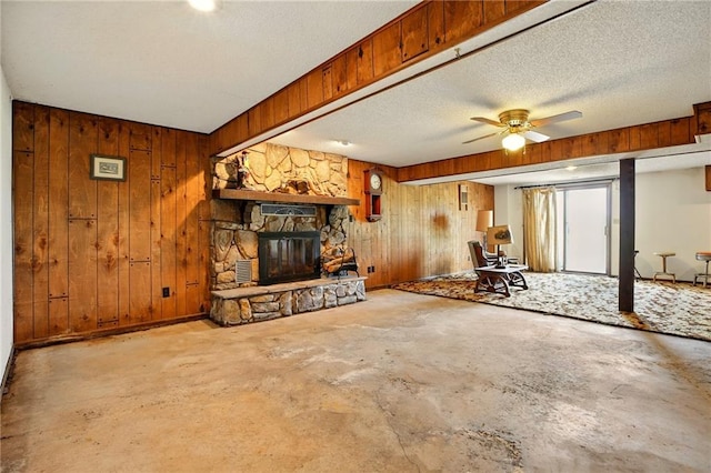 4613 SE Atchison Rd, Lathrop, MO 64465 - unfurnished living room with concrete flooring, wood walls, a fireplace, ceiling fan, and a textured ceiling