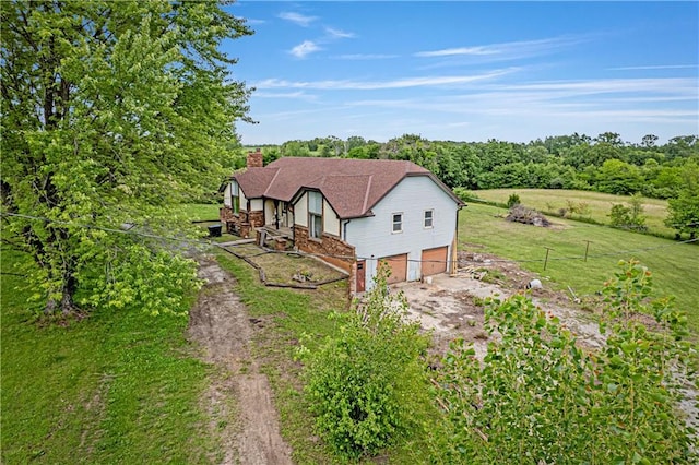 4613 SE Atchison Rd, Lathrop, MO 64465 - view of front facade with dirt driveway, a chimney, an attached garage, brick siding, and a front yard