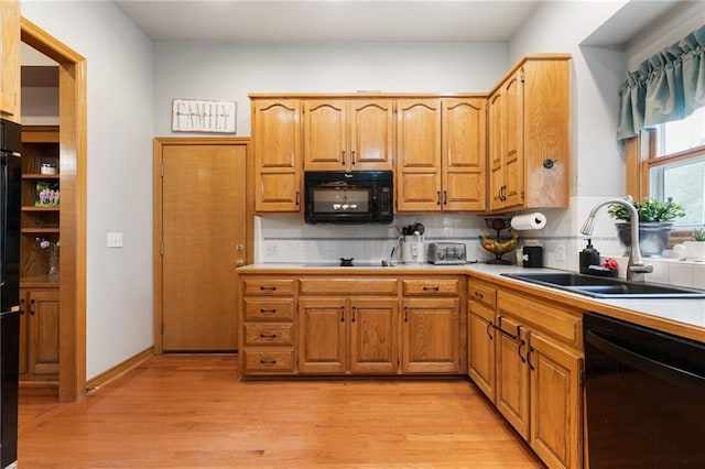 12484 S Hallet St, Olathe, KS 66062 - kitchen featuring black appliances, a sink, light wood-style floors, and backsplash