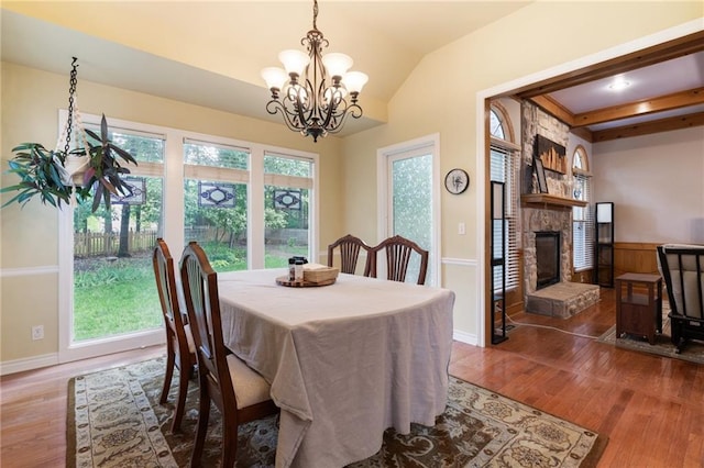 12484 S Hallet St, Olathe, KS 66062 - dining area featuring wood finished floors, a chandelier, a fireplace, vaulted ceiling, and baseboards