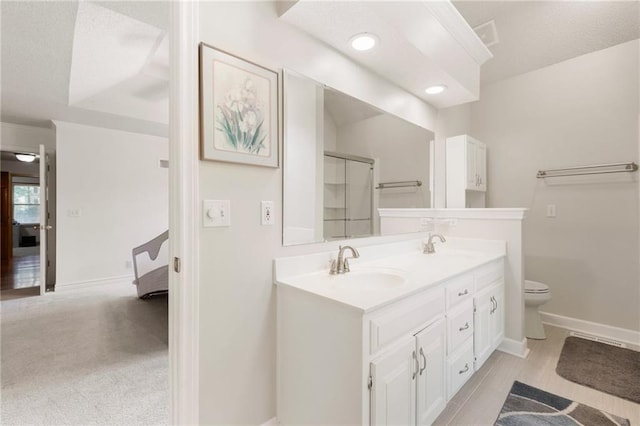 12484 S Hallet St, Olathe, KS 66062 - full bathroom featuring double vanity, toilet, baseboards, a shower with shower door, and recessed lighting
