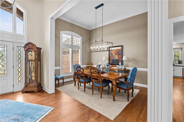 724 NE Seabrook Cir, Lees Summit, MO 64064 - dining area featuring wood finished floors, ornate columns, crown molding, baseboards, and a chandelier