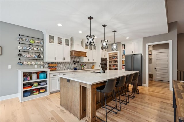 3112 Legacy Wood Dr, Lees Summit, MO 64086 - kitchen with premium range hood, black appliances, a sink, white cabinets, and light wood-style floors