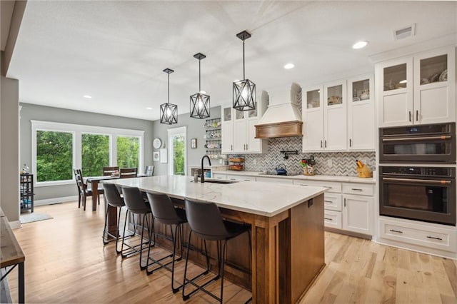 3112 Legacy Wood Dr, Lees Summit, MO 64086 - kitchen with a sink, premium range hood, black appliances, light wood-style flooring, and backsplash