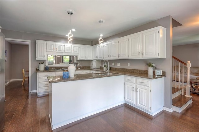 21614 W 72nd St, Shawnee, KS 66218 - kitchen with dark stone counters, dark wood-style flooring, white cabinets, a sink, and decorative light fixtures