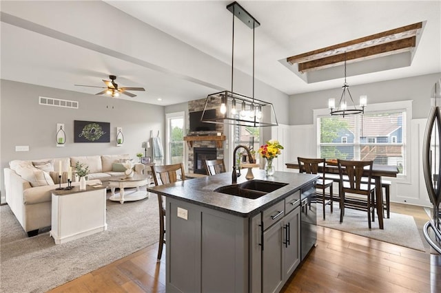 481 Olive Ct, Warrensburg, MO 64093 - kitchen featuring a sink, a raised ceiling, stainless steel dishwasher, a stone fireplace, and dark countertops