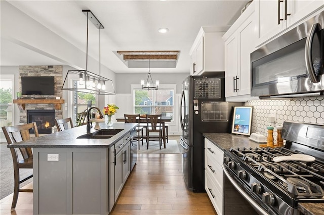481 Olive Ct, Warrensburg, MO 64093 - kitchen with appliances with stainless steel finishes, a sink, a raised ceiling, a stone fireplace, and healthy amount of natural light