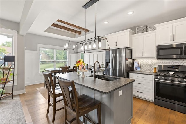 481 Olive Ct, Warrensburg, MO 64093 - kitchen featuring stainless steel appliances, a sink, dark countertops, a kitchen breakfast bar, and a chandelier