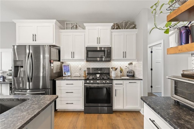 481 Olive Ct, Warrensburg, MO 64093 - kitchen with appliances with stainless steel finishes, white cabinetry, backsplash, light wood finished floors, and dark stone countertops