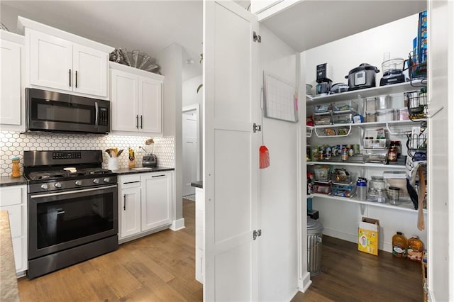 481 Olive Ct, Warrensburg, MO 64093 - kitchen featuring stainless steel appliances, light wood-style floors, white cabinets, backsplash, and dark countertops
