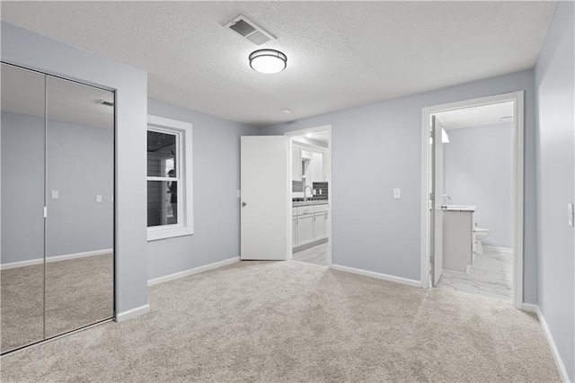 1709 Marty Ave, Kansas City, KS 66103 - unfurnished bedroom featuring carpet flooring, a closet, ensuite bathroom, baseboards, and a textured ceiling
