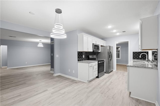 1709 Marty Ave, Kansas City, KS 66103 - kitchen featuring appliances with stainless steel finishes, a sink, tasteful backsplash, light wood-type flooring, and white cabinets
