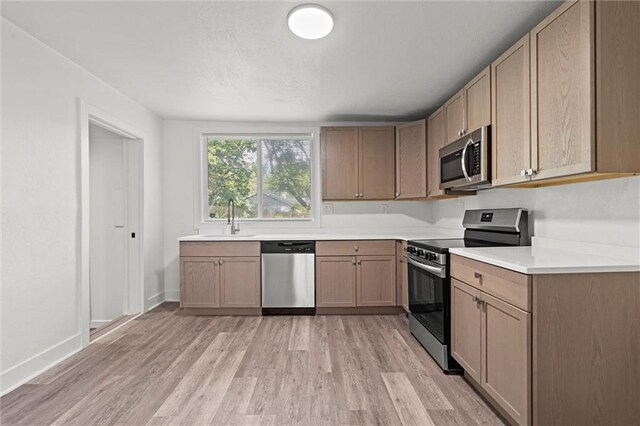 6 W 98th Ter, Kansas City, MO 64114 - kitchen with stainless steel appliances, a sink, light wood-style floors, and light countertops