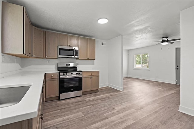 6 W 98th Ter, Kansas City, MO 64114 - kitchen featuring appliances with stainless steel finishes, ceiling fan, light wood-type flooring, baseboards, and a textured ceiling