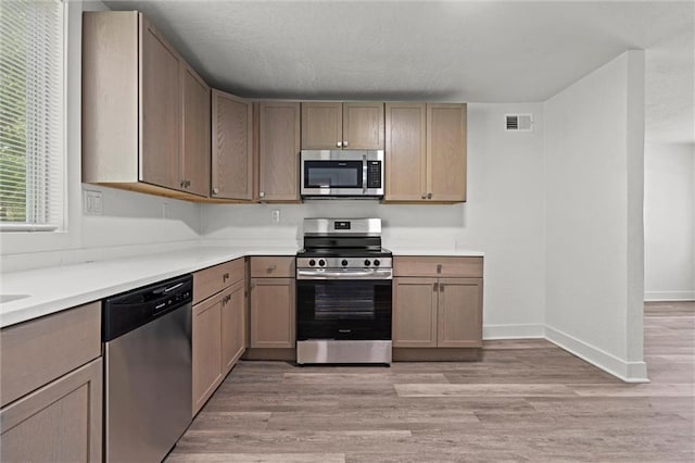 6 W 98th Ter, Kansas City, MO 64114 - kitchen with appliances with stainless steel finishes, light wood-style floors, light countertops, and baseboards