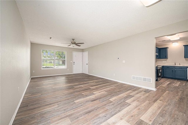 214 NW Parker Dr, Grain Valley, MO 64029 - unfurnished living room with light wood finished floors, a sink, and baseboards