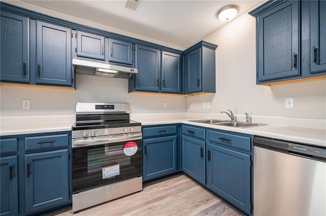 214 NW Parker Dr, Grain Valley, MO 64029 - kitchen featuring stainless steel appliances, a sink, under cabinet range hood, blue cabinetry, and light wood-type flooring