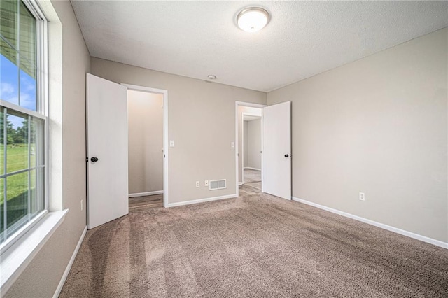 214 NW Parker Dr, Grain Valley, MO 64029 - unfurnished bedroom with multiple windows, carpet flooring, baseboards, and a textured ceiling