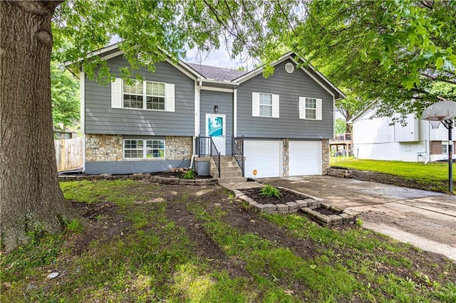 516 S St, Grain Valley, MO 64029 - split foyer home featuring concrete driveway, stone siding, and an attached garage