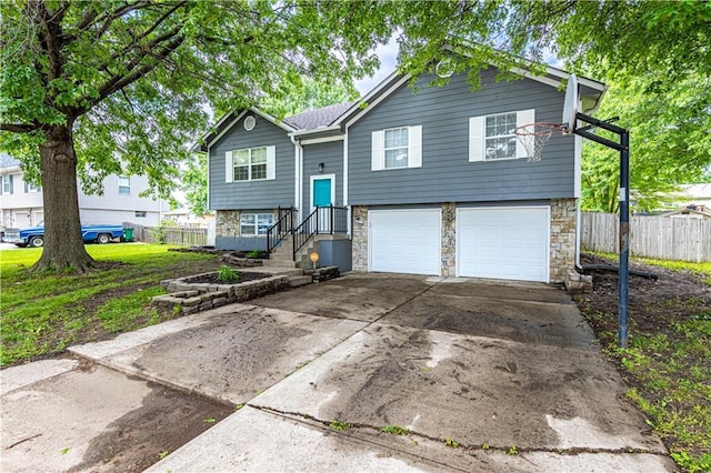 516 S St, Grain Valley, MO 64029 - split foyer home with stone siding, an attached garage, and concrete driveway