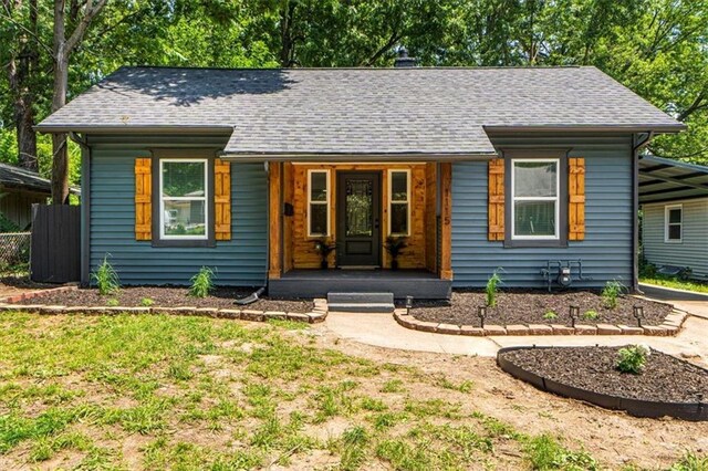 1115 S Leslie St, Independence, MO 64050 - bungalow featuring a porch, a carport, a shingled roof, and driveway