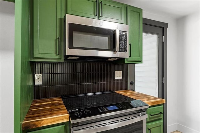 1115 S Leslie St, Independence, MO 64050 - kitchen with green cabinetry, wooden counters, and stainless steel microwave
