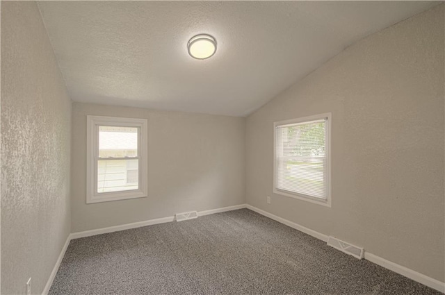 11300 Greenwood Rd, Kansas City, MO 64134 - empty room with vaulted ceiling, carpet floors, a textured wall, baseboards, and a textured ceiling