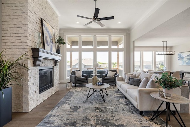 19477 W 114th Ter, Olathe, KS 66061 - living room featuring a ceiling fan, a stone fireplace, wood finished floors, crown molding, and recessed lighting